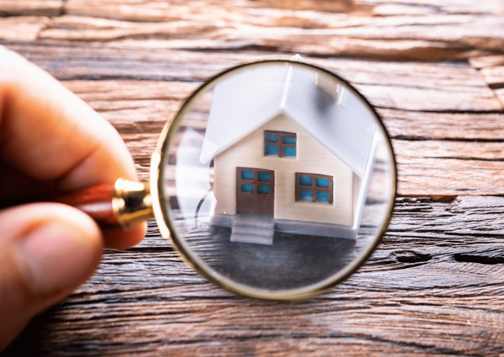 Maison miniature vue au travers d'une loupe pour illustrer la vente en infraction urbanistique à Bruxelles.